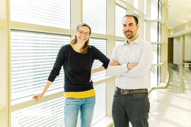 Two researchers stand beside one another in a hallway.