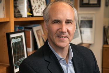 A close-up photograph of researcher Daniel Geschwind smiling in his office before a bookshelf.