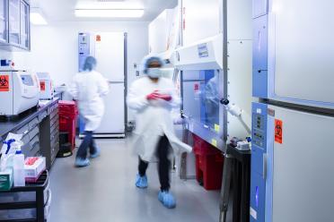 Scientists walk around in a UCLA laboratory wearing full PPE.