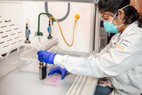 A masked UCLA researcher extracts contents from a vape for testing. 