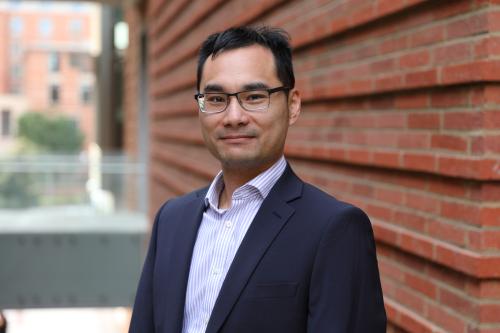 Researcher Neil Lin smiles in a headshot taken outside. 