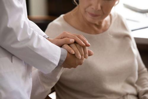 A doctor gently holds a patient's hand.