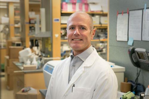 Headshot of S. Thomas Carmichael in a lab coat smiles in a UCLA lab