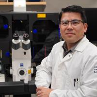 Ken Yamauchi standing next to microscope